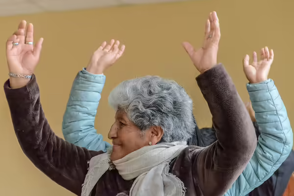 woman with grey hair head turned hands above head
