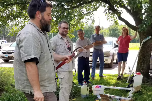 A group of people outside examine a tool