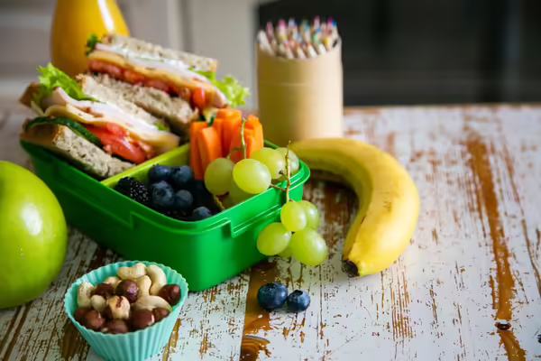 healthy school lunch in a lunch box with sandwich, banana, grapes and nuts