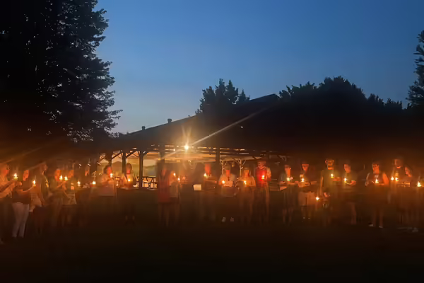 Attendees gather in a candlelight circle.