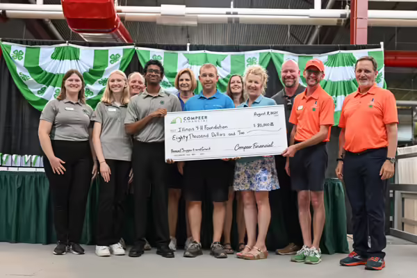 Staff from ACES and COMPEER pose around a giant check.