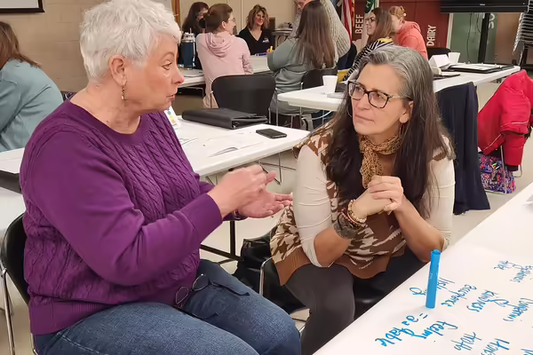 two women sitting at a table talking to each other