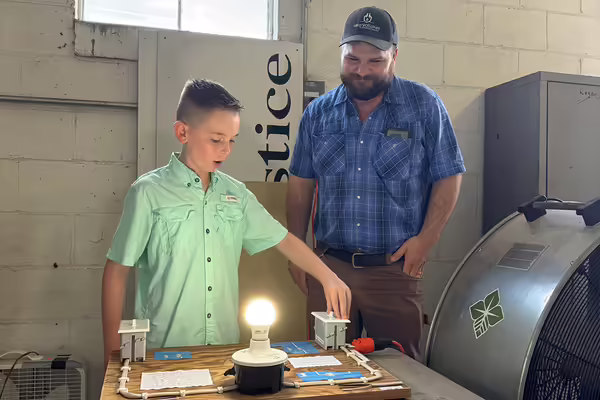 a 4-H member demonstrates his electricity project exhibit to a judge