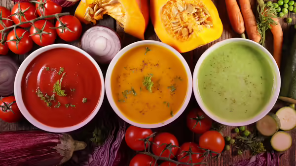 bowls of soup with various vegetables in the background