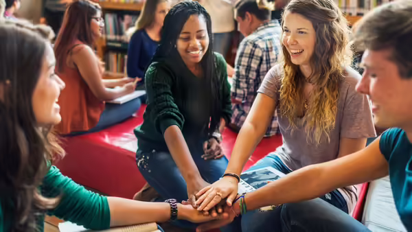 youth sitting with their arms outstretched and hands stacked in the middle of them