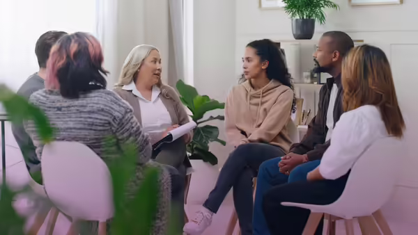 half circle group of people in chairs discussing with each other