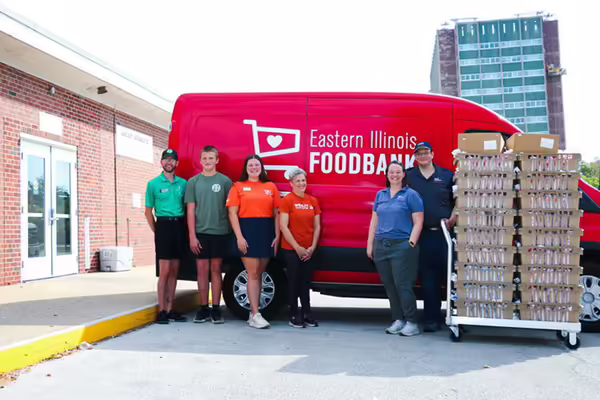A group of six people pose next to a food bank truck filled with meat donations for communities