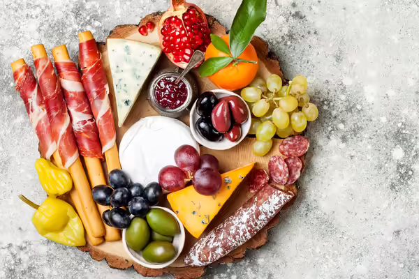 A charcuterie board with meats, cheeses, fruits and veggies