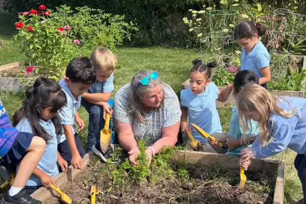 Nancy surrounded by a group of kids gardening