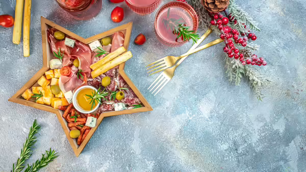 Charcuterie platter with ham, prosciutto, salami, cheese, crackers and olives on the board in the form of a Christmas star
