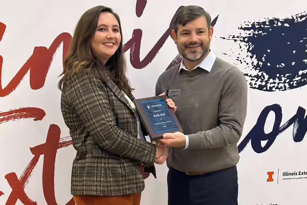 Katie Bell holding plaque next to Extension Director