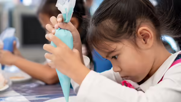 a little girl decorating a cupcake