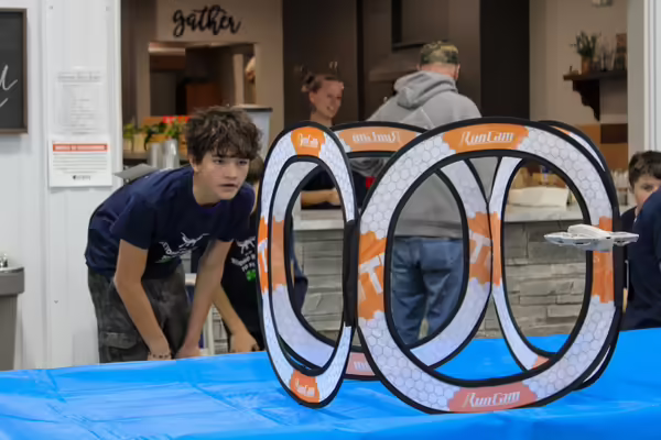 A participant through an obstacle, watching closely to ensure a drone flies through it safely.