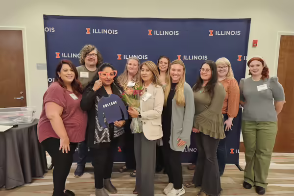 A group of people standing in front of a University of Illinois backdrop