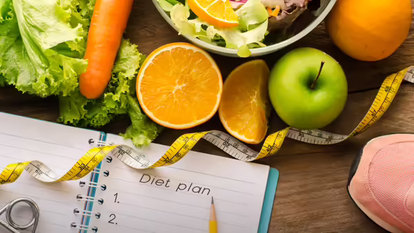 A diet plan notebook, a measuring tape, fruits, and vegetables.