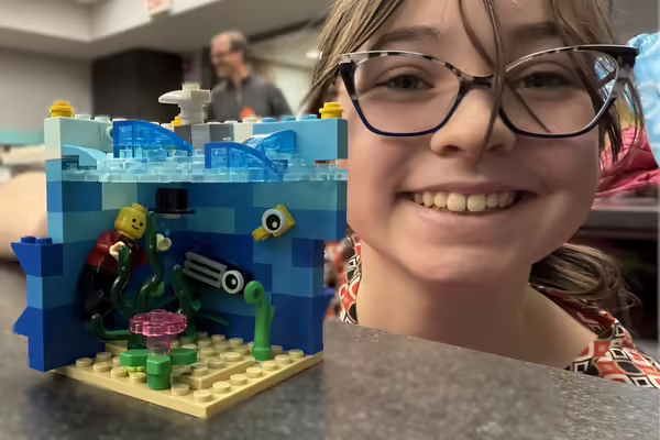 Winner poses with Lego build featuring an under the sea creation.
