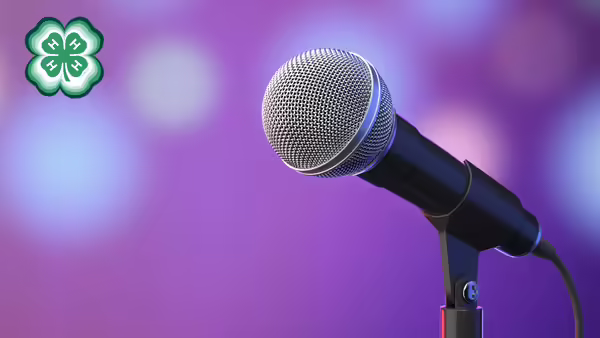 A microphone with a purple background. A green 4-H clover in the upper left corner.