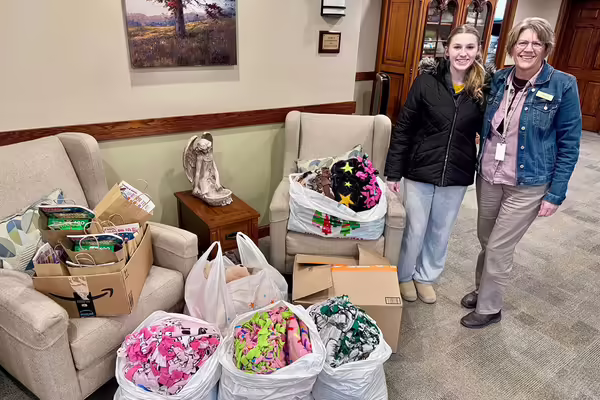 Two people standing next to bags of blankets
