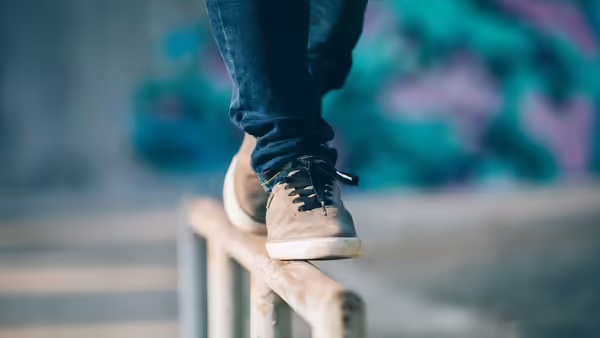 A close up of a person's feet as they balance on a steel bar.