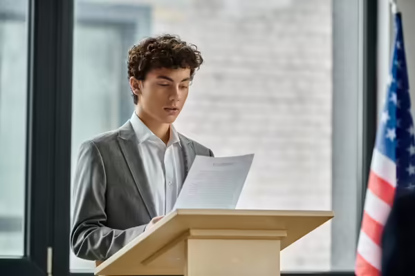 Youth at podium with papers in hand for a speech 