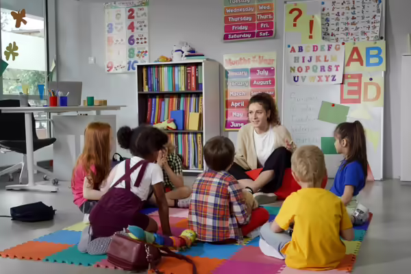 A teacher on the floor with her preschool students 