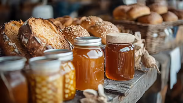 A table with jars of honey and fresh baked bread. 