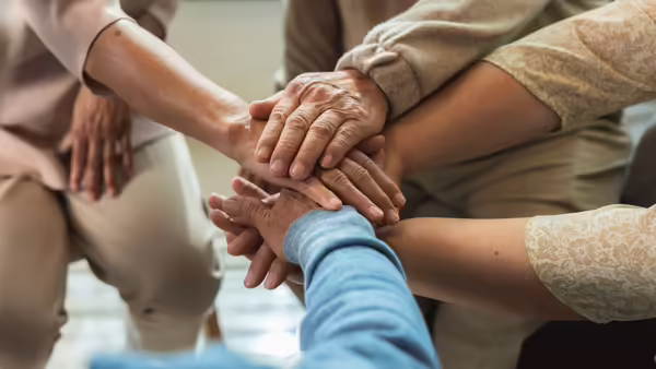 A group of people of different races, holding each others hands. 