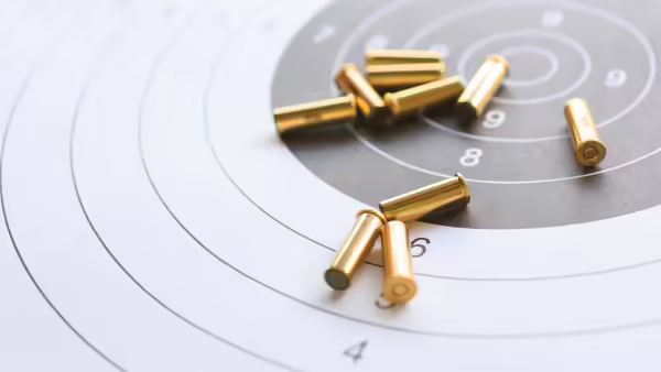 A white paper target with gold bullet shells laying on top.