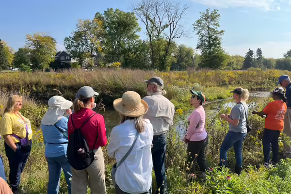 A group of Master Naturalists standing in a field by a river