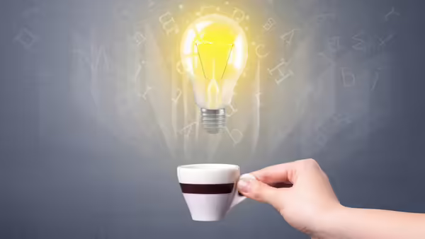 A white coffee mug with a black stripe with a light bulb coming out of the center.