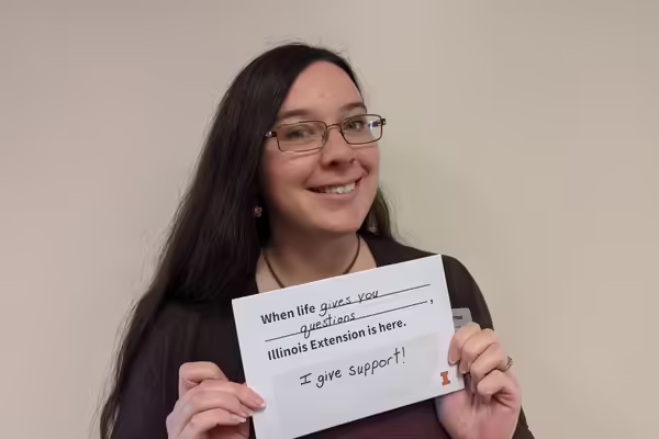 Olivia holds a sign that reads "when life gives you questions, Illinois Extension gives you support"