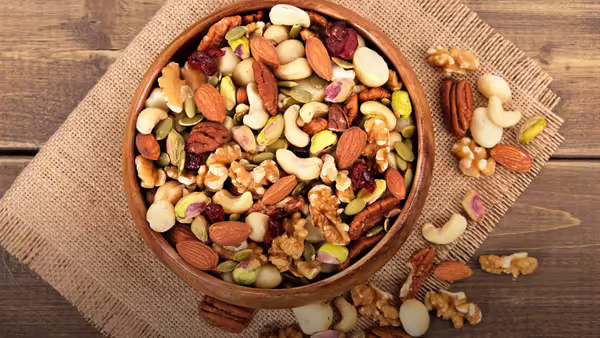 A wooden bowl filled with a variety of mixed nuts and seeds.