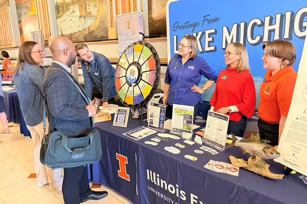 People at a table talk to others a sign in the background says "Lake Michigan"