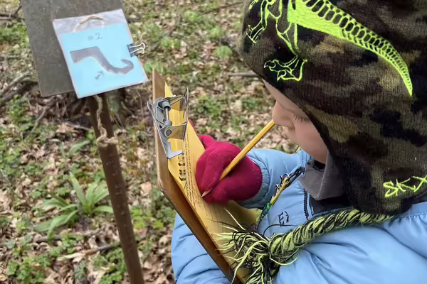 child with clipboard, paper, and pencil outside