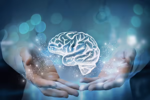 A pair of hands holding a digital brain with a cloud of activity around it.