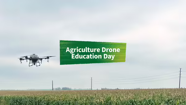 A spray drone in the distance flying over a corn field.
