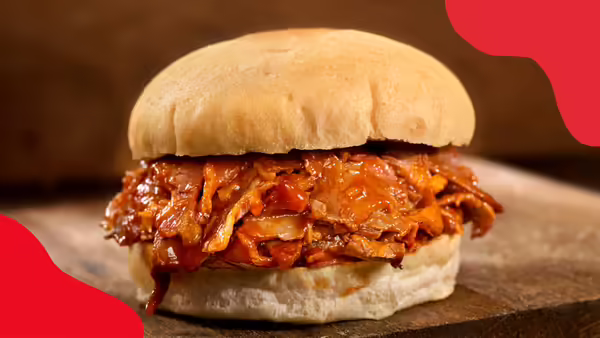 A pulled pork sandwich on a wooden cutting board.