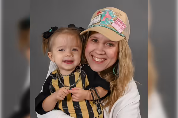 Brooke wears a hat and holds a young child in her lap