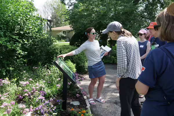 Woman showing gardeners a pollinator garden. 