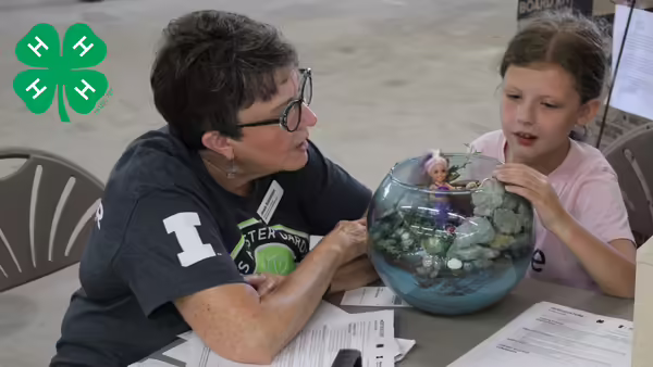 Woman and youth presenting a project with a green clover on the left hand corner