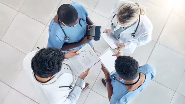 four people wearing medical career clothing, standing in a circle