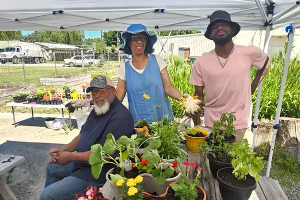 man, woman, young man standing in front of plants in containers