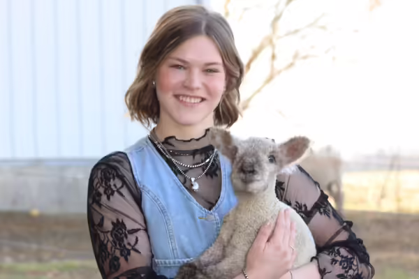 Molly McCalla holding a lamb in her arms.