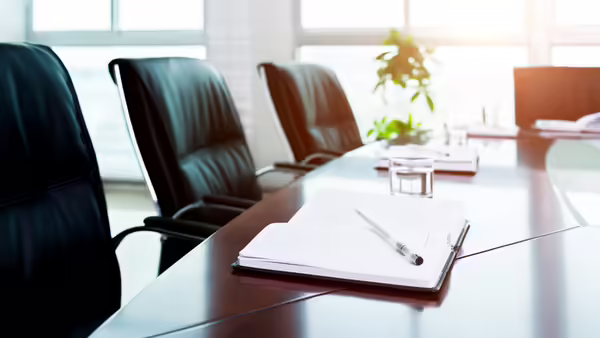 A boardroom meeting with a notepad and pen on the table.