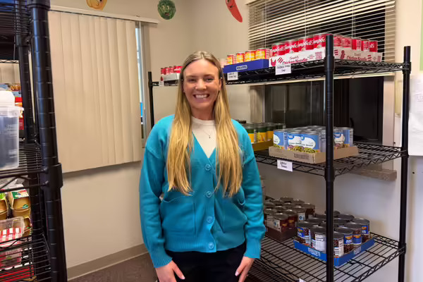 Morgan stands in front of a food pantry shelf