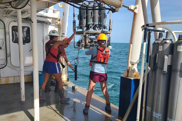 two women in hard hats use machinery on a boat in the ocean