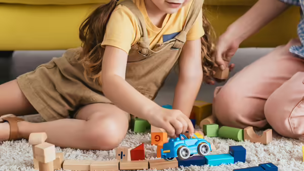 a child and adult sitting on the floor playing with toys
