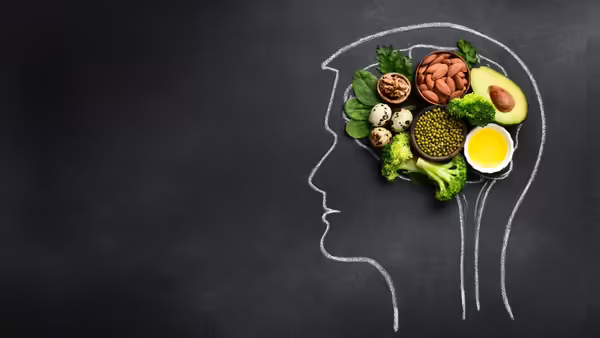 Chalkboard background with white chalk outline of male head. Brain-healthy foods on top of the board in the shape of a brain