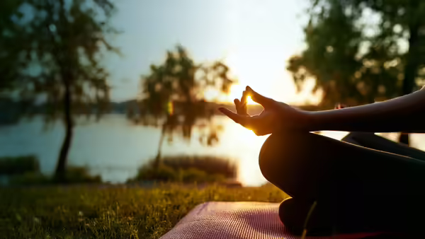 person doing yoga by pond
