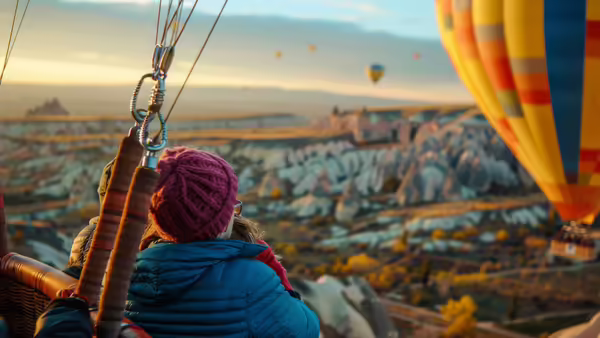 People in a hot air balloon gazing out at the horizon and other floating hot air balloons. 